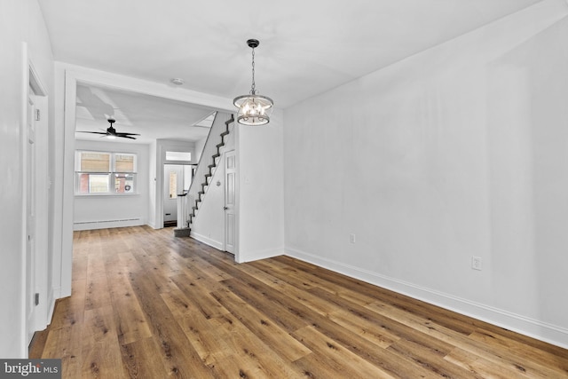 unfurnished dining area with a baseboard heating unit, baseboards, stairway, hardwood / wood-style floors, and an inviting chandelier