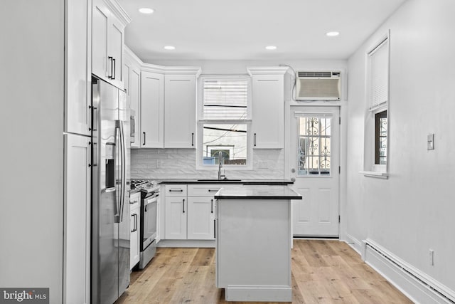 kitchen featuring stainless steel appliances, a baseboard radiator, dark countertops, a sink, and a wall mounted air conditioner