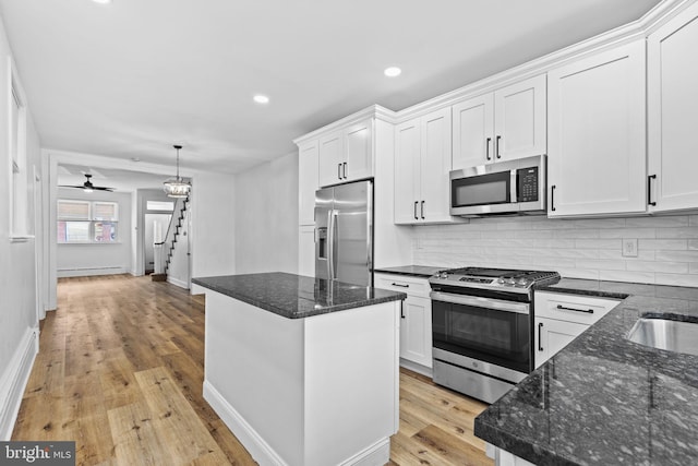 kitchen featuring light wood-type flooring, white cabinetry, stainless steel appliances, and decorative backsplash