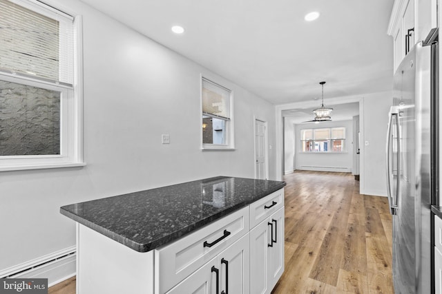 kitchen featuring light wood-type flooring, white cabinetry, a baseboard heating unit, and stainless steel refrigerator