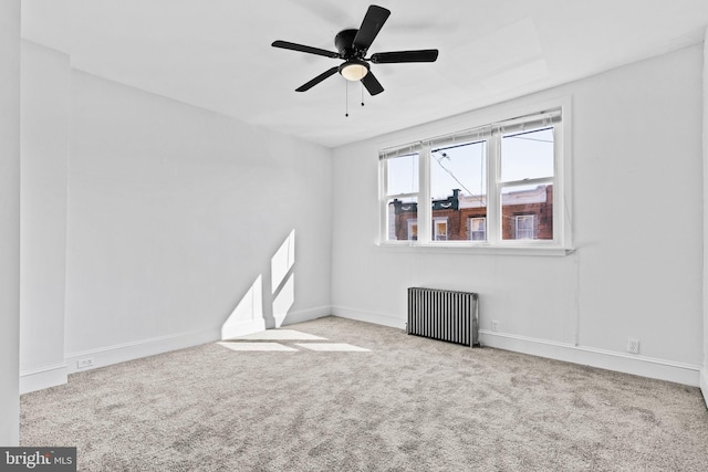 empty room featuring a ceiling fan, carpet, baseboards, and radiator heating unit