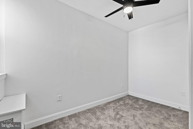 carpeted spare room featuring baseboards and a ceiling fan