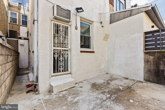 doorway to property featuring a patio area, a wall mounted AC, and stucco siding