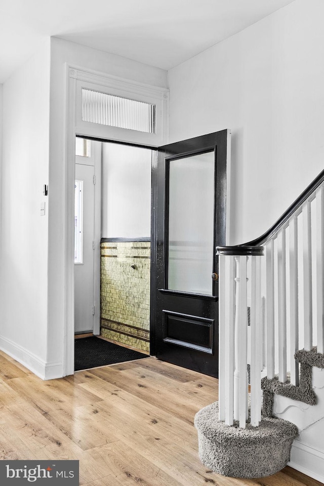 foyer entrance featuring stairs, wood finished floors, and baseboards