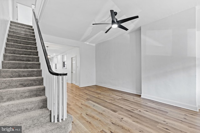 stairway with lofted ceiling, a ceiling fan, baseboards, and wood finished floors