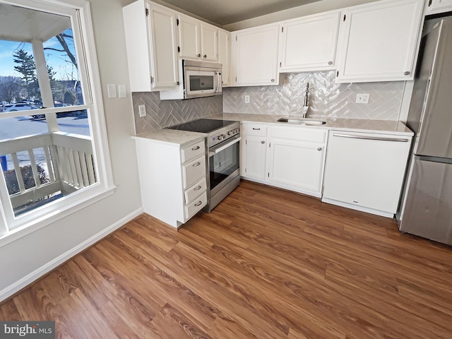 kitchen featuring stainless steel appliances, decorative backsplash, dark wood-type flooring, white cabinets, and a sink