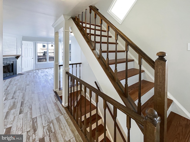 stairway with ornate columns, a fireplace, and baseboards