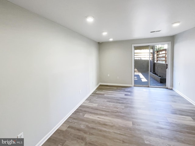 spare room featuring wood finished floors, visible vents, and baseboards