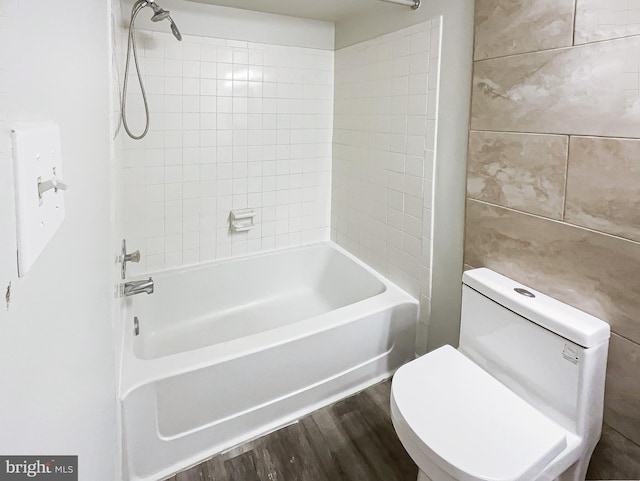 bathroom featuring toilet, tile walls, shower / washtub combination, and wood finished floors