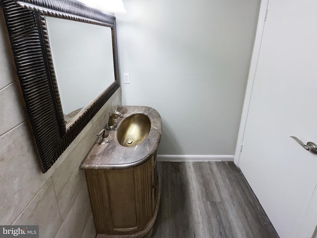 half bath featuring baseboards, wood finished floors, and vanity