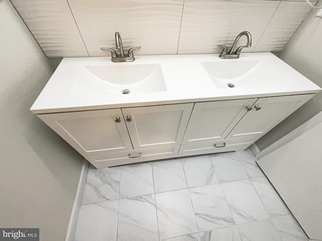 bathroom featuring double vanity, marble finish floor, and a sink