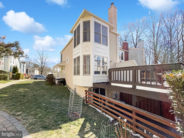 view of property exterior with a lawn, a chimney, and a wooden deck