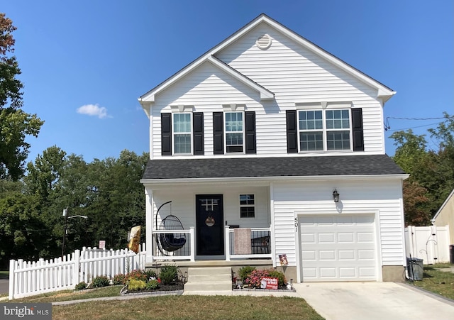 traditional-style house featuring a porch, a shingled roof, concrete driveway, fence, and a garage