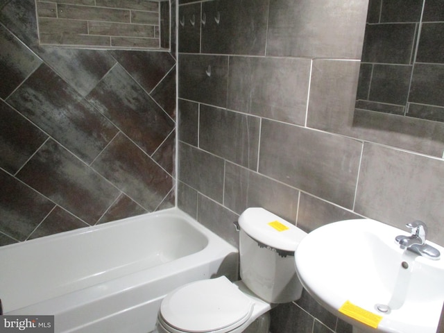 full bath featuring a tub, a sink, tile walls, and toilet