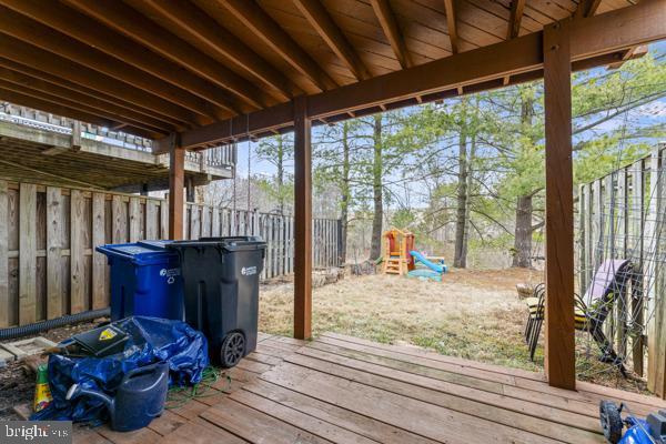 wooden terrace with a fenced backyard and a playground