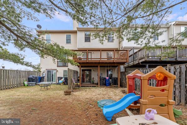 back of house featuring a playground, a yard, a chimney, fence, and a deck