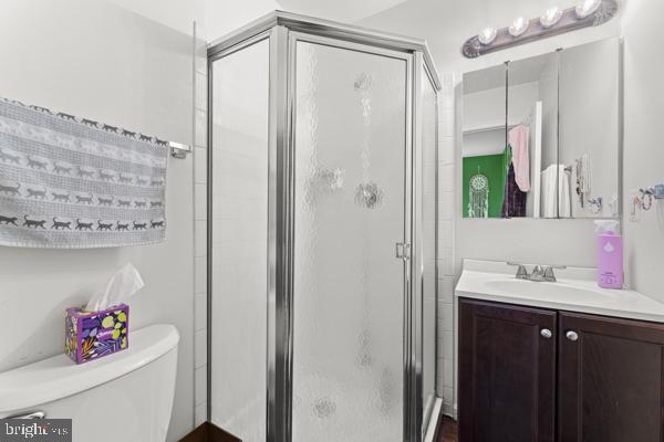 bathroom featuring toilet, a shower stall, and vanity