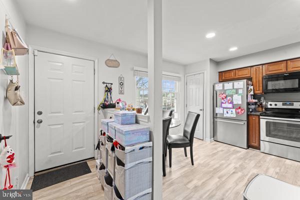 kitchen with baseboards, brown cabinetry, stainless steel appliances, light wood-type flooring, and recessed lighting