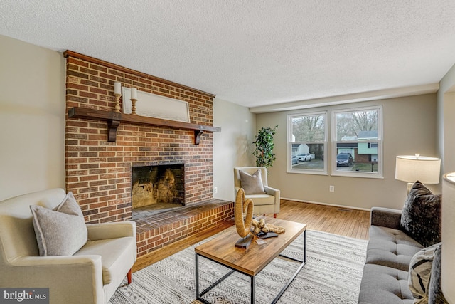 living room with a fireplace, a textured ceiling, and wood finished floors