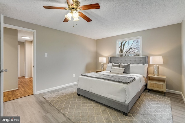 bedroom with ceiling fan, a textured ceiling, baseboards, and wood finished floors