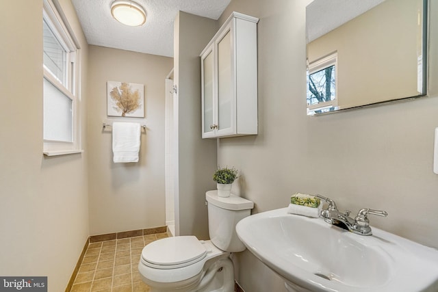 full bath featuring toilet, a textured ceiling, walk in shower, and a sink