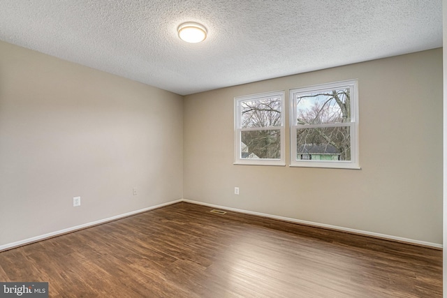 unfurnished room with visible vents, a textured ceiling, baseboards, and wood finished floors