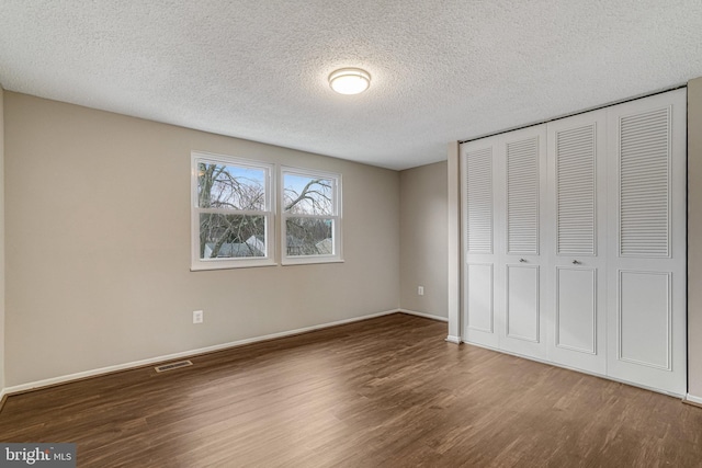 unfurnished bedroom featuring a closet, wood finished floors, visible vents, and baseboards