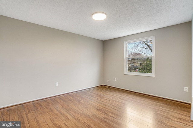 spare room featuring a textured ceiling, wood finished floors, and baseboards