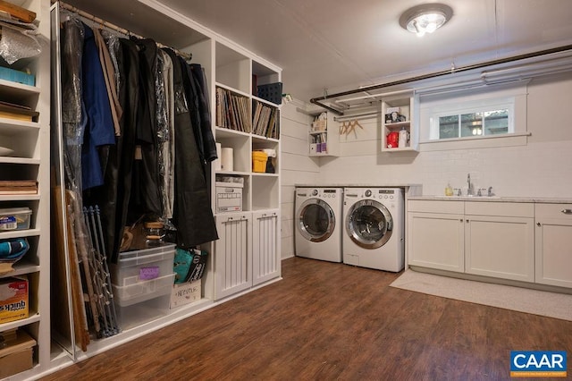 washroom with a sink, dark wood-style flooring, washing machine and dryer, and cabinet space