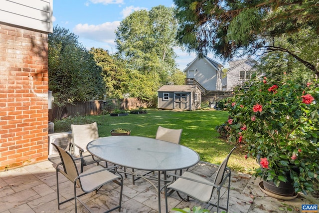 view of patio / terrace with an outbuilding, outdoor dining area, a fenced backyard, and a storage unit