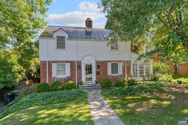 view of front of house featuring metal roof, brick siding, a standing seam roof, and a chimney