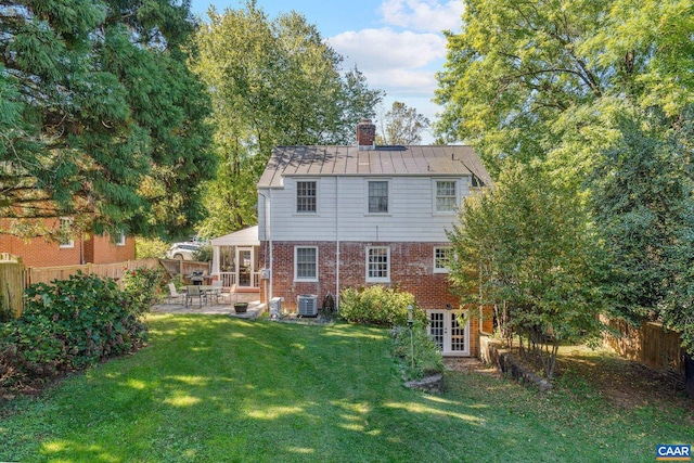 rear view of property featuring a lawn, a patio, a fenced backyard, a chimney, and brick siding