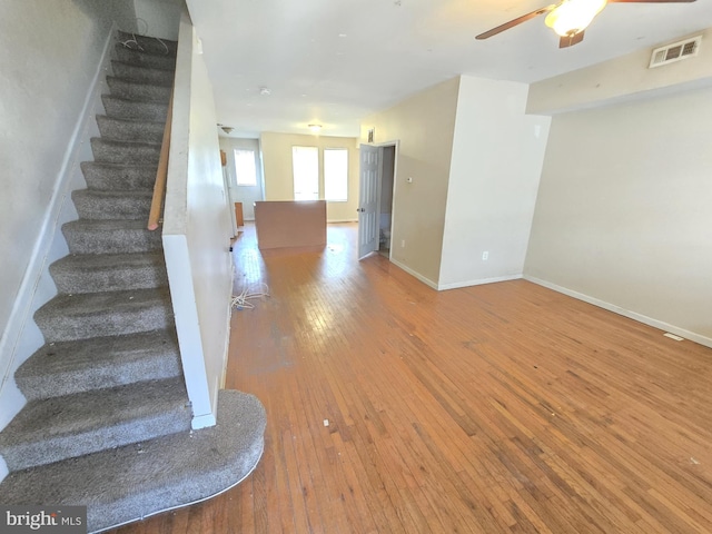 interior space featuring baseboards, visible vents, ceiling fan, and hardwood / wood-style floors