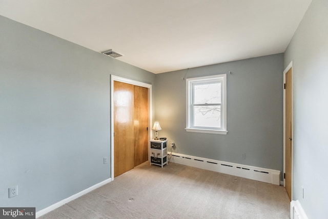 carpeted empty room featuring baseboard heating, a baseboard radiator, visible vents, and baseboards