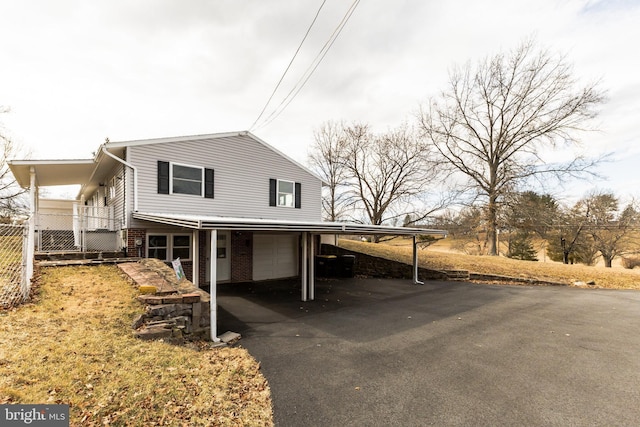 view of front of property featuring a garage, aphalt driveway, an attached carport, fence, and brick siding