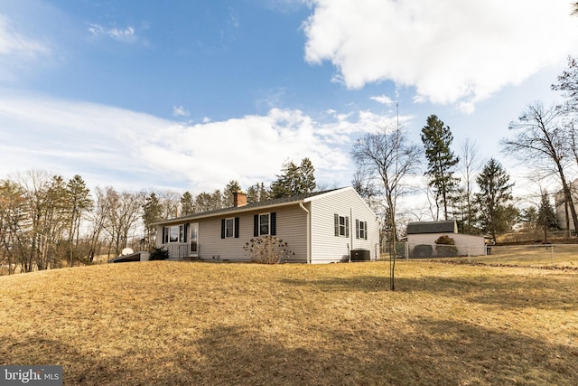 view of side of property with a chimney, a lawn, and central air condition unit