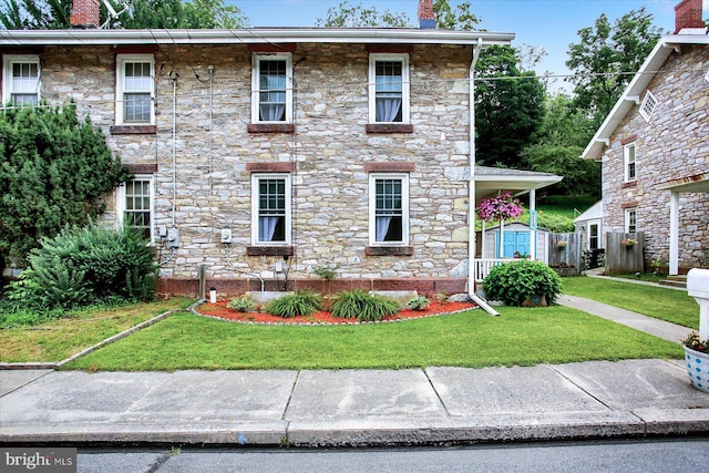 view of front of property featuring a storage shed, a front lawn, and a chimney