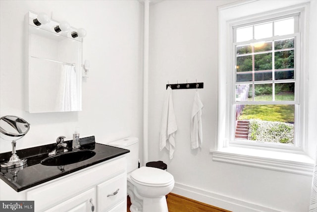 bathroom with toilet, a shower with shower curtain, wood finished floors, vanity, and baseboards