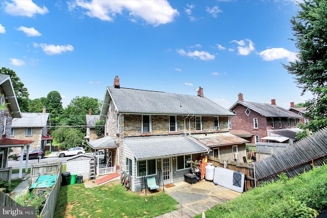 rear view of property with stone siding, a yard, and fence