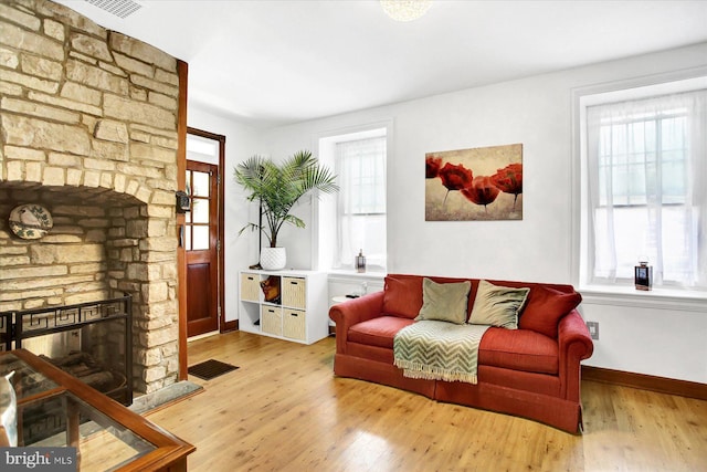 sitting room featuring baseboards, a fireplace, visible vents, and wood finished floors