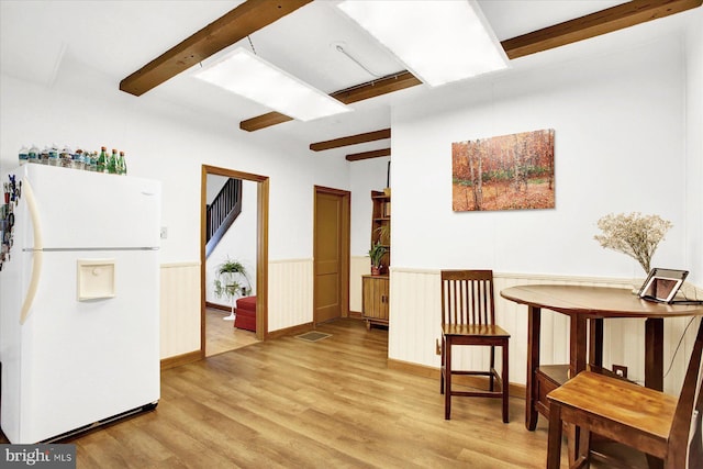 sitting room with light wood-style floors, stairway, beam ceiling, and a wainscoted wall