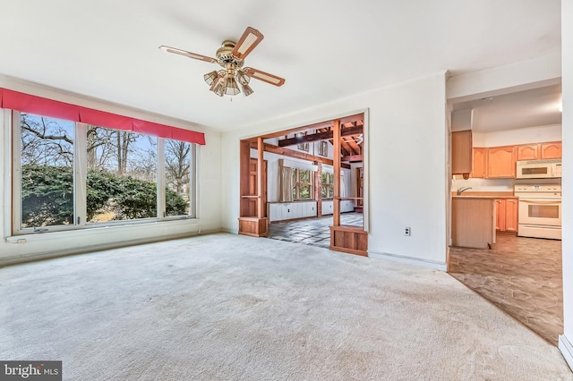 unfurnished living room with carpet floors, a baseboard heating unit, ceiling fan, and baseboards