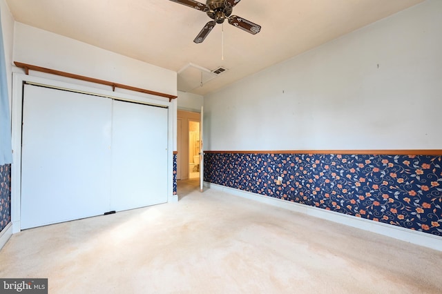 unfurnished bedroom with ceiling fan, carpet flooring, visible vents, a closet, and attic access