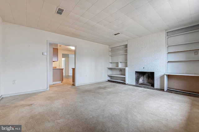 unfurnished living room featuring built in features, baseboards, visible vents, carpet flooring, and a brick fireplace