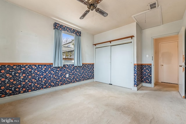 carpeted spare room with a wainscoted wall, visible vents, a ceiling fan, attic access, and wallpapered walls