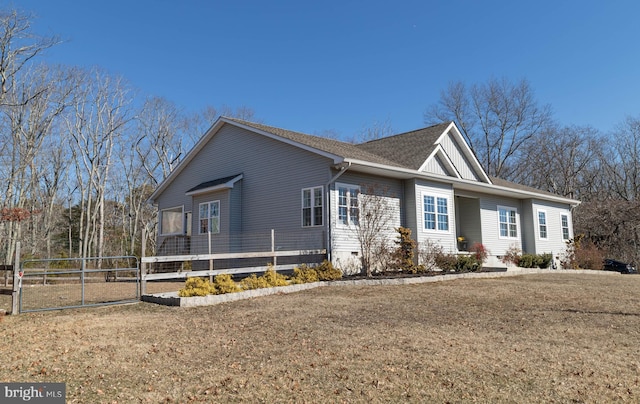 ranch-style house featuring a shingled roof, a front yard, and fence