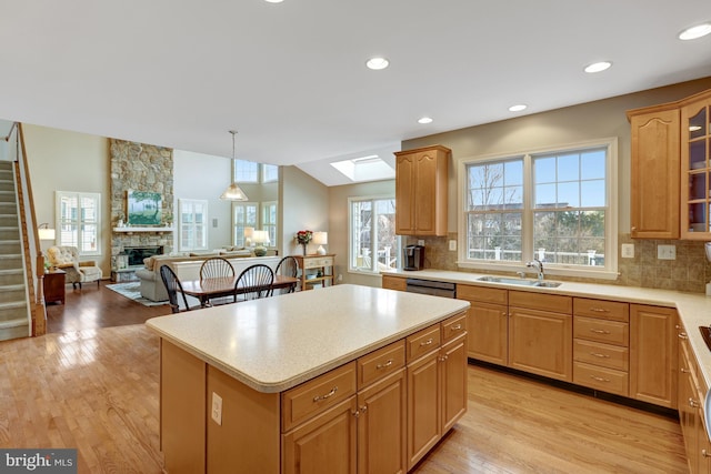 kitchen featuring a wealth of natural light, light wood-style floors, a stone fireplace, and light countertops