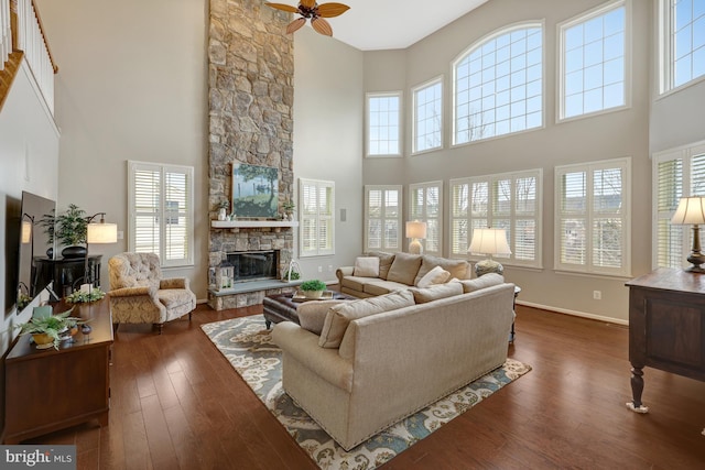 living room with ceiling fan, baseboards, dark wood-style floors, and a fireplace