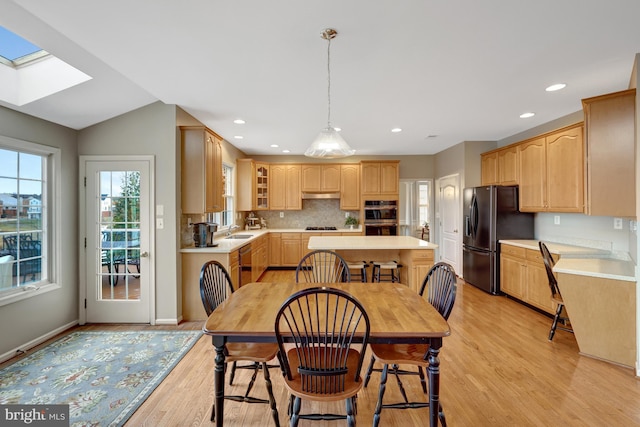 dining room featuring light wood finished floors, recessed lighting, a skylight, and baseboards