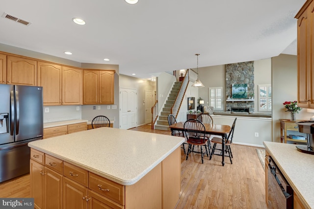 kitchen with visible vents, black fridge, a fireplace, and light countertops